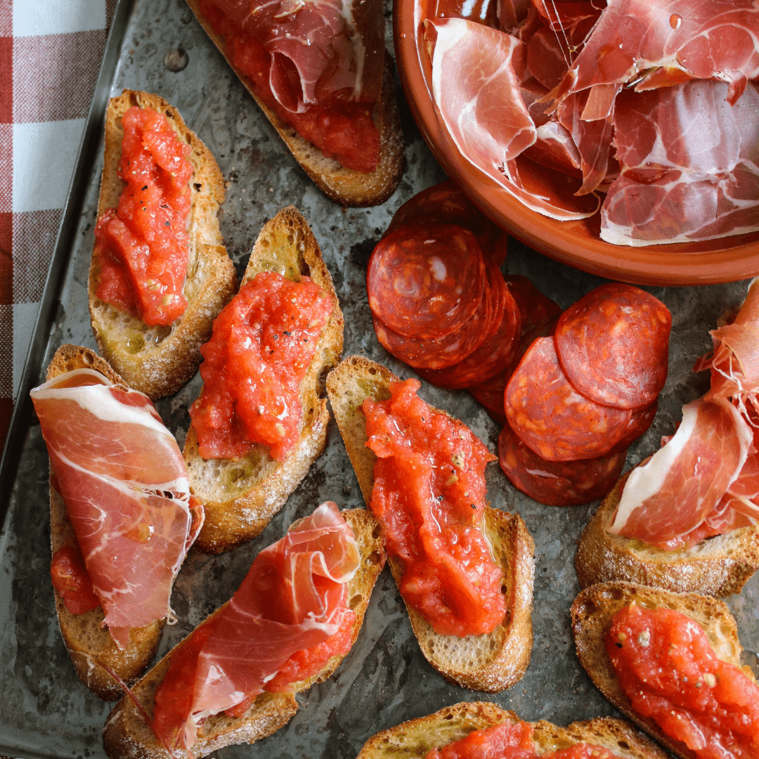 Rostat bröd med riven tomat och tunna skivor serranoskinka ovanpå.