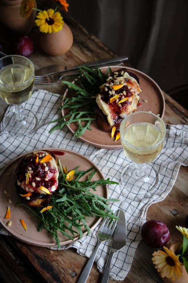 Chevre chaud med betor och plommon på tallrikar med glas med halvtorr mousserande B.R.O.T. Cava