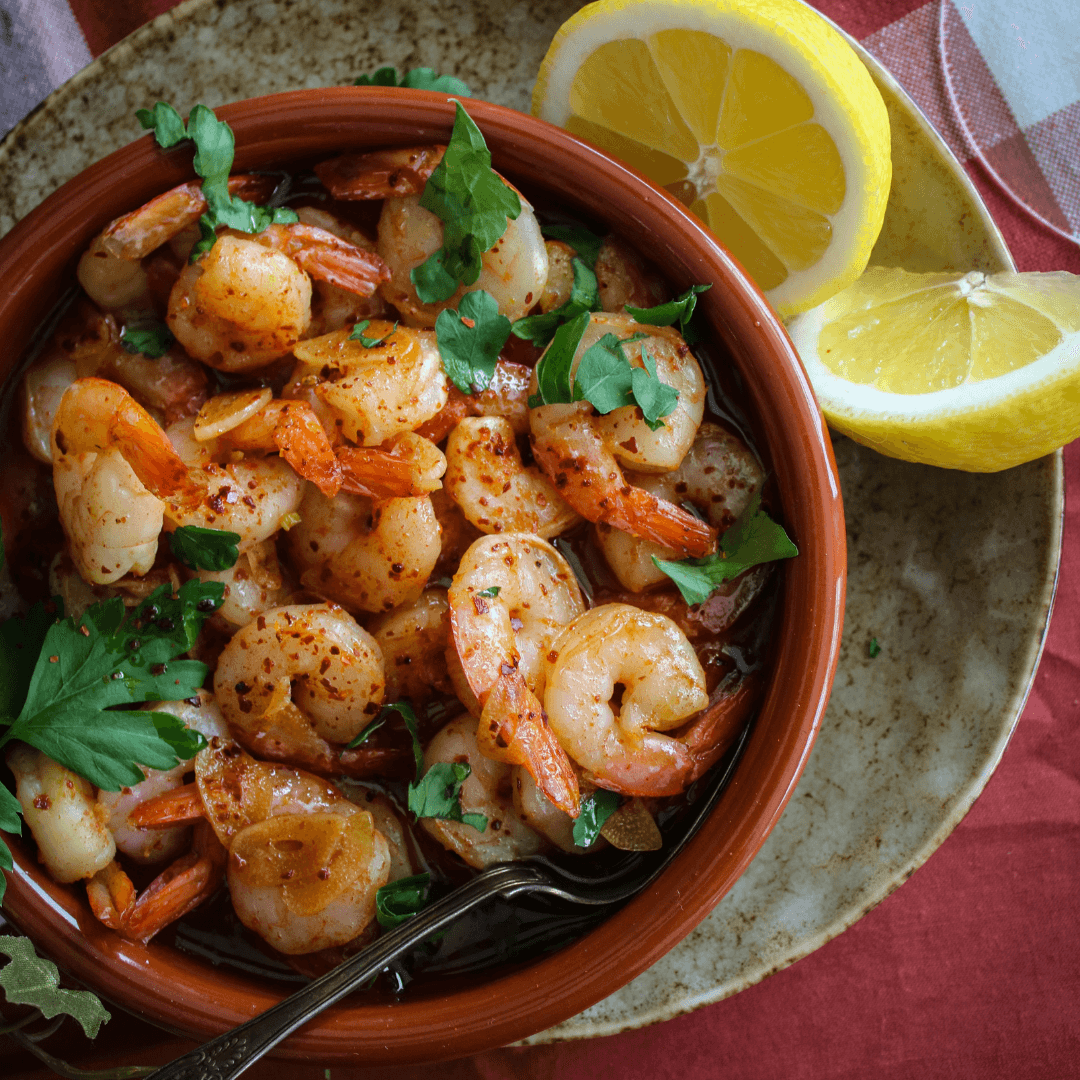 Räkor frästa i olivolja med vitlök och chili, toppade med persilja i en liten panna.