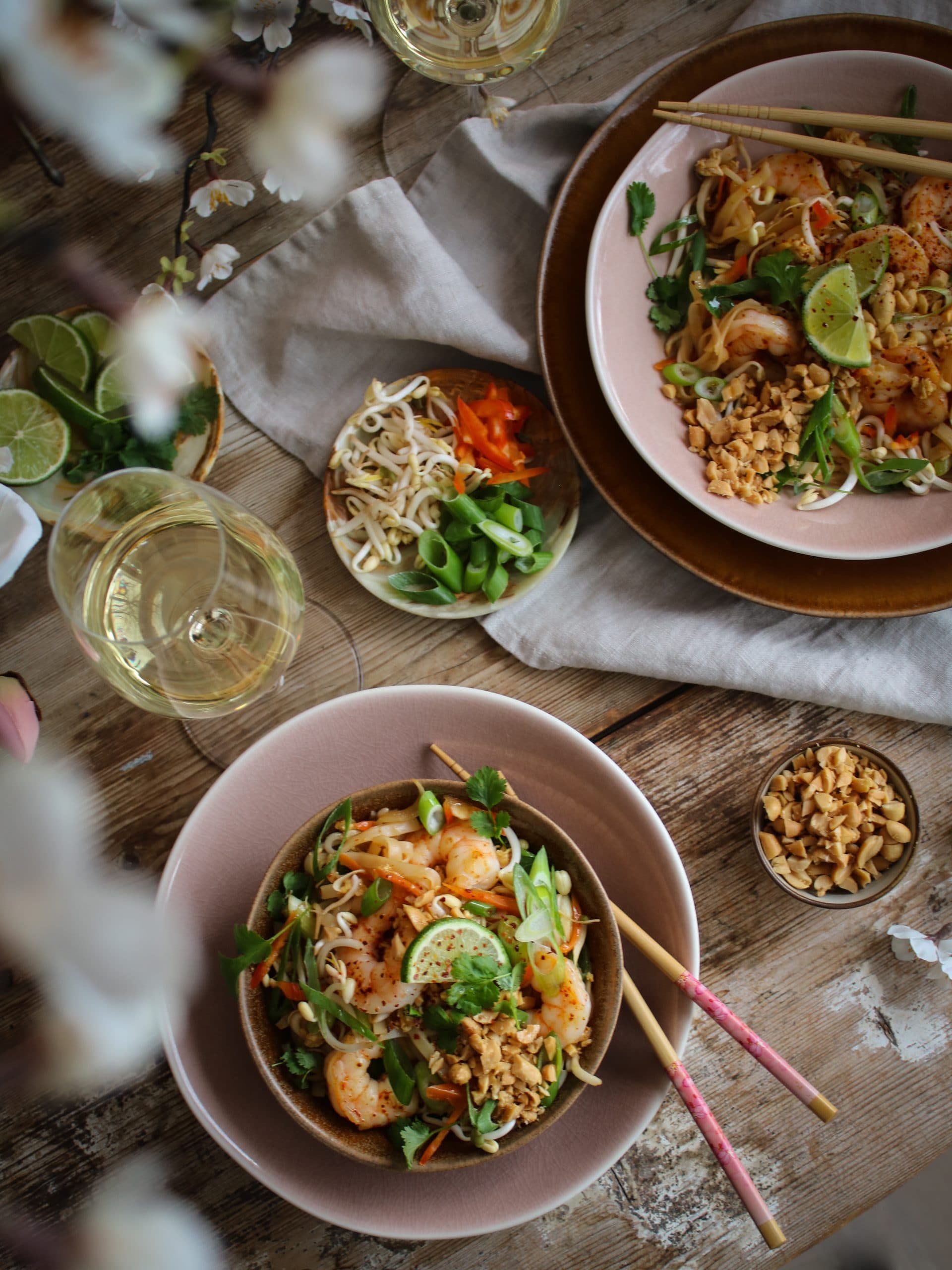 Pad thai med räkor med en vårig dukning i rosa och ett halvtorrt vin.