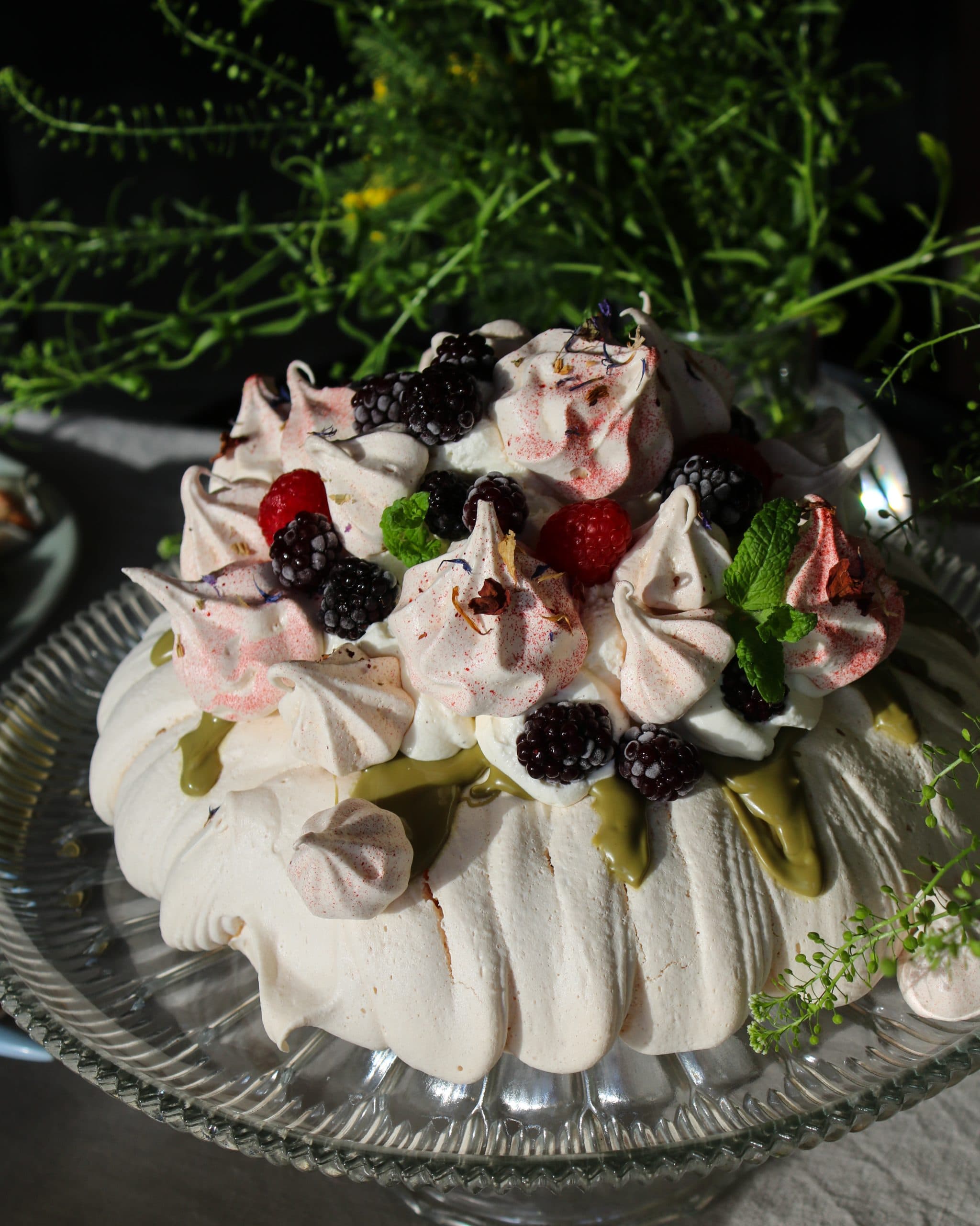 Påskpavlova med krämig fyllning, pistagenötter och färska bär.